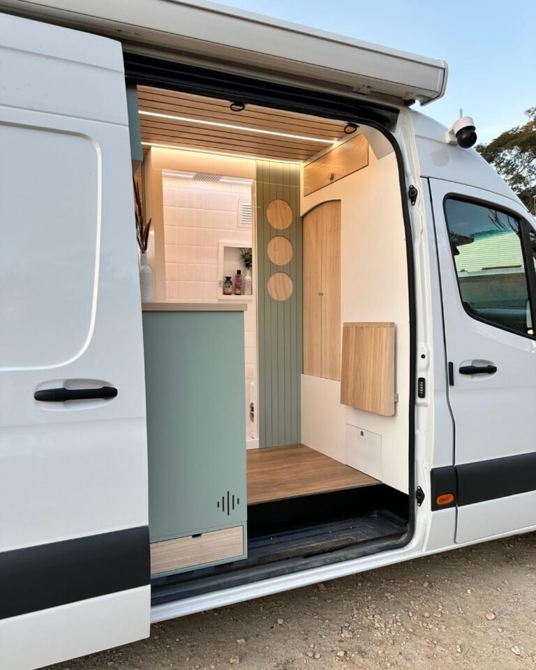 Área de entrada do motorhome Sprinter 416 Extra Longa, com mesa retrátil e banco embutido, em design moderno.