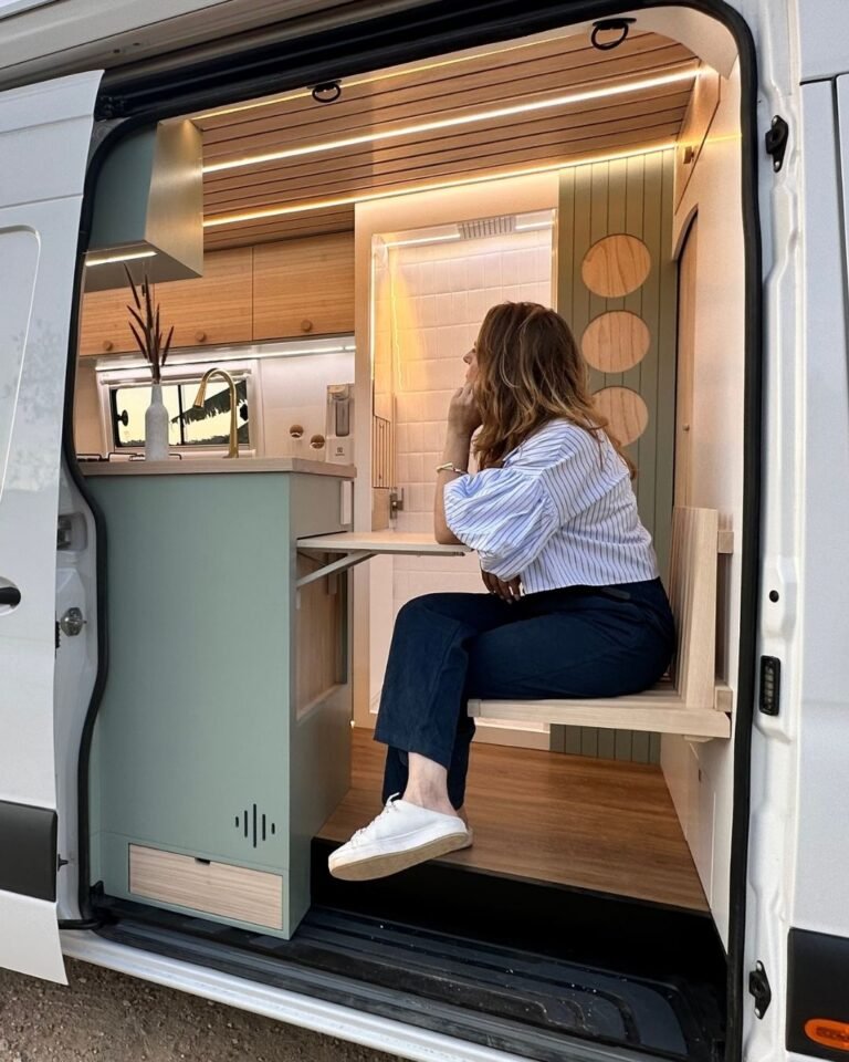 Área de entrada da Sprinter 416 Extra Longa, com mesa retrátil e banco embutido, em design moderno.