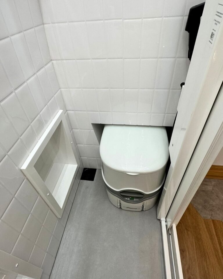 Banheiro da Sprinter Trio com vaso portátil e chuveiro, em design compacto e funcional, ideal para viagens em família.