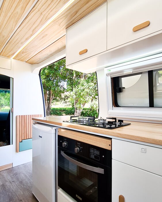 Cozinha compacta da Sprinter 416 Extra Longa, com fogão, pia, geladeira e armários em tons claros e design moderno